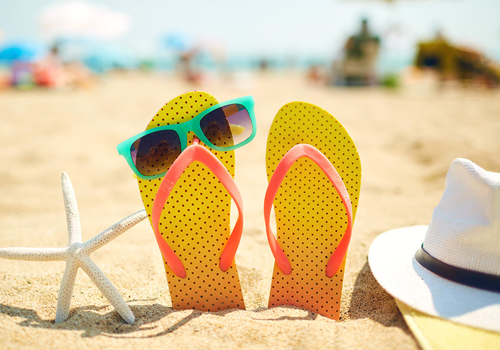 Bunter Sommerlatschen am Strand als Symbol für den Ferienbeginn Bunter Sommerlatschen am Strand als Symbol für den Ferienbeginn